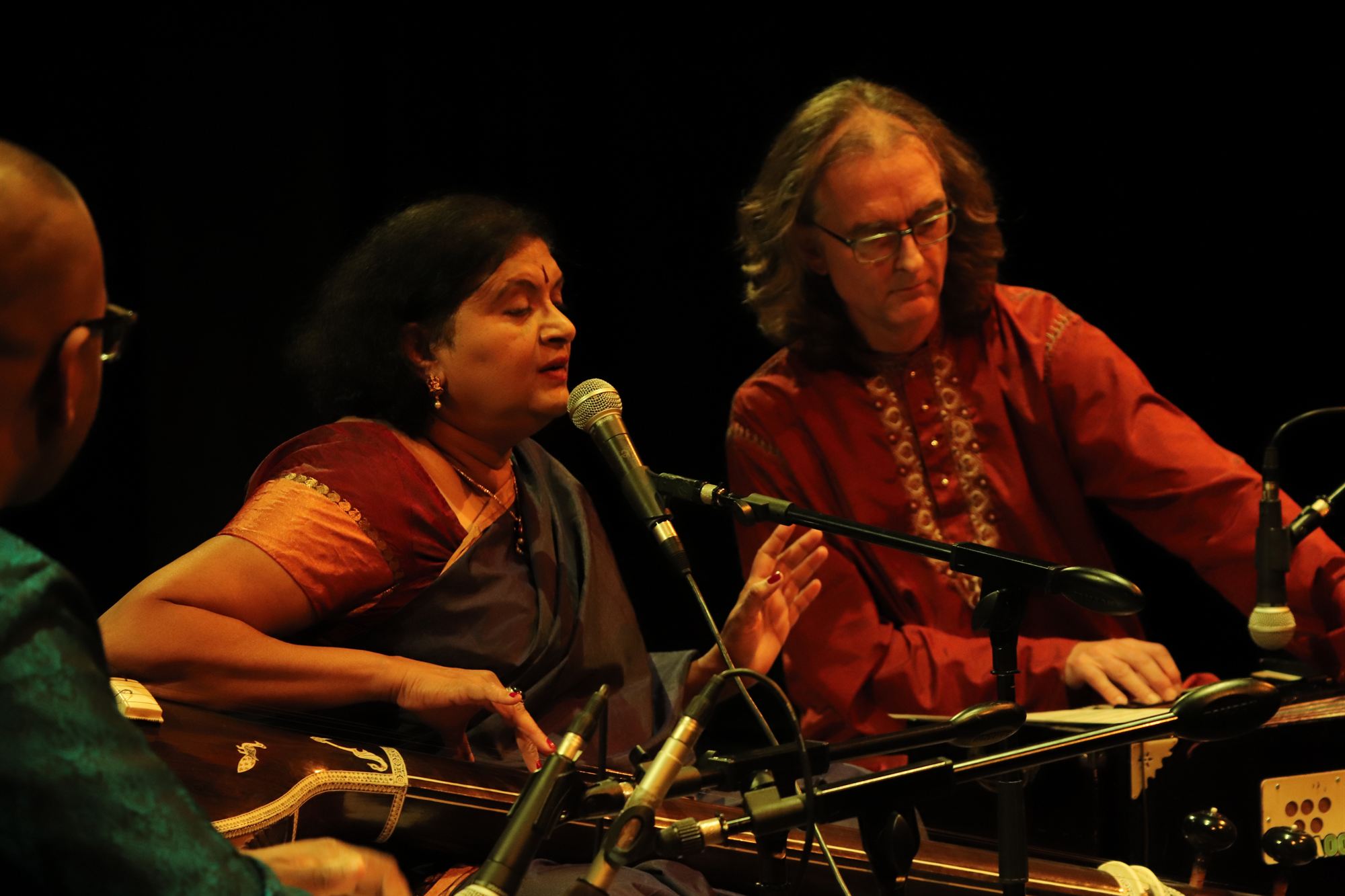 Zangeres aan het harmonium tijdens een concert, met begeleiding