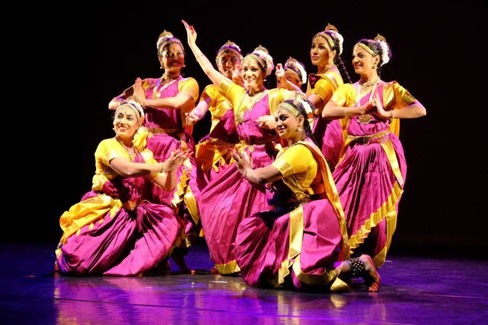 Dansgroep in paarse en gele kostuums op het podium: Ashta Lakshmi